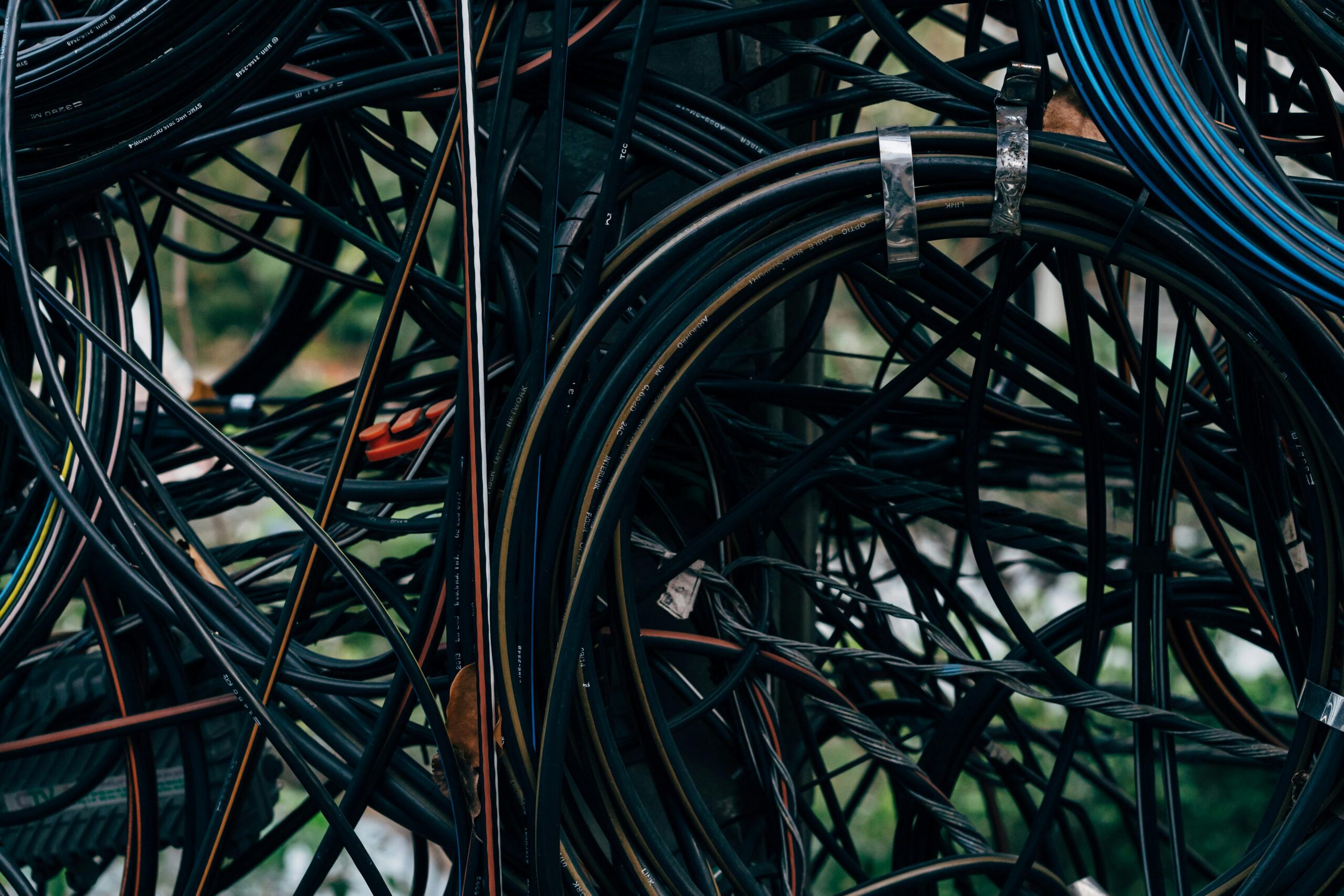 Close-up view of a complex tangle of electrical wires outdoors.